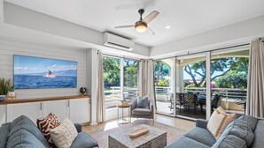 Una sala de estar moderna con un televisor grande, asientos cómodos y vistas al exterior.