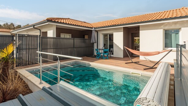 Ein modernes Haus mit Swimmingpool, einem umzäunten Patio und einer Hängematte.
