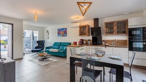 Eine moderne Küche mit Holzschränken, einem schwarzen Kühlschrank und einem Essbereich mit Tisch für zwei Personen.