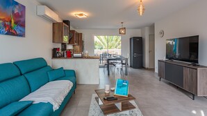 Ein modernes Wohnzimmer mit einem türkisfarbenen Sofa, einem Couchtisch und einem Fernseher.