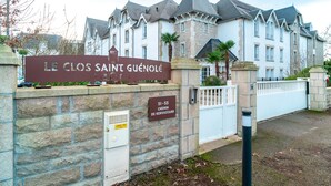 A stone wall with a sign for "Le Clos Saint Guénolé" and a gate.