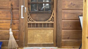 Une porte en bois avec une fenêtre, un balai et un paillasson.