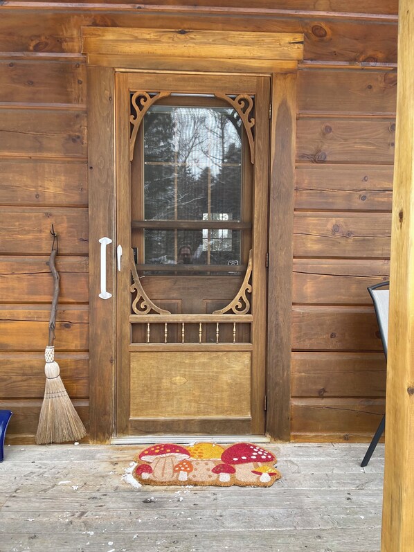 A wooden door with a window, a broom, and a doormat.