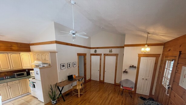Un vaste espace de vie doté de planchers en bois, d’un ventilateur de plafond et d’une table à manger avec des chaises.