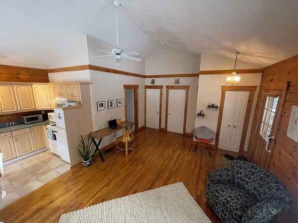 A spacious living area with wooden floors, a ceiling fan, and a dining table with chairs.