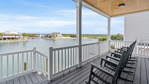 A covered outdoor deck with a view of a calm body of water and distant buildings. - Simply Blessed- 5BR/5.5BA Channel House-Pool (North Myrtle Beach)