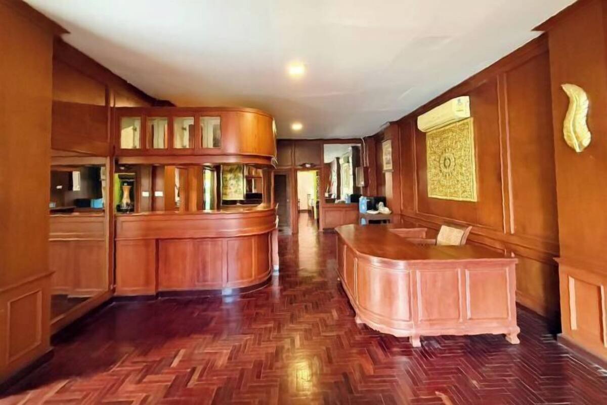 A hotel lobby with wooden paneling, a herringbone-patterned floor, a reception desk, and a decorative wall piece.