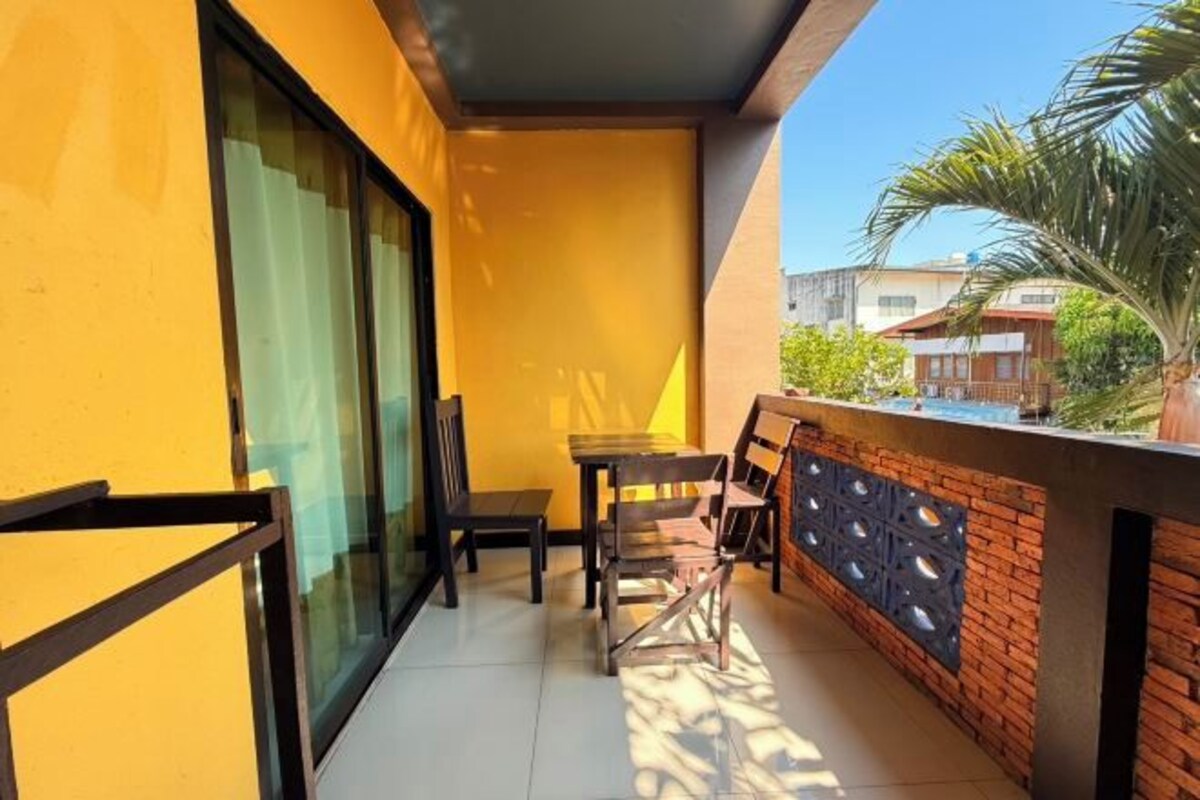 A balcony with a table and chairs, a glass door, and a brick wall with decorative cutouts.