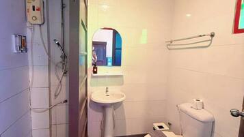 A bathroom with a toilet, sink, shower, and a mirror.