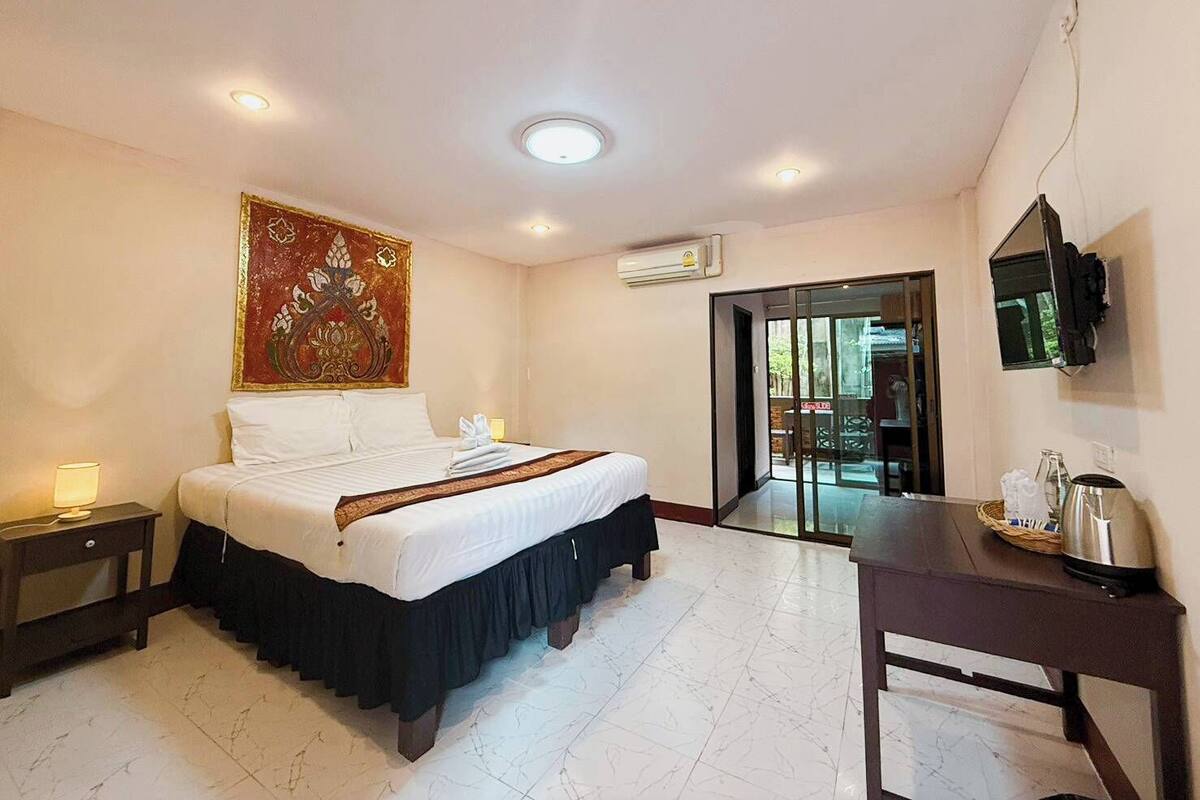 A hotel room with a bed, a desk, a TV, and a large window.