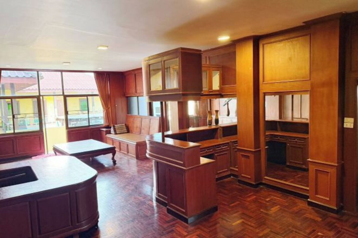 A spacious kitchen with wooden cabinetry, a dining area with a table and chairs, and large windows allowing natural light.