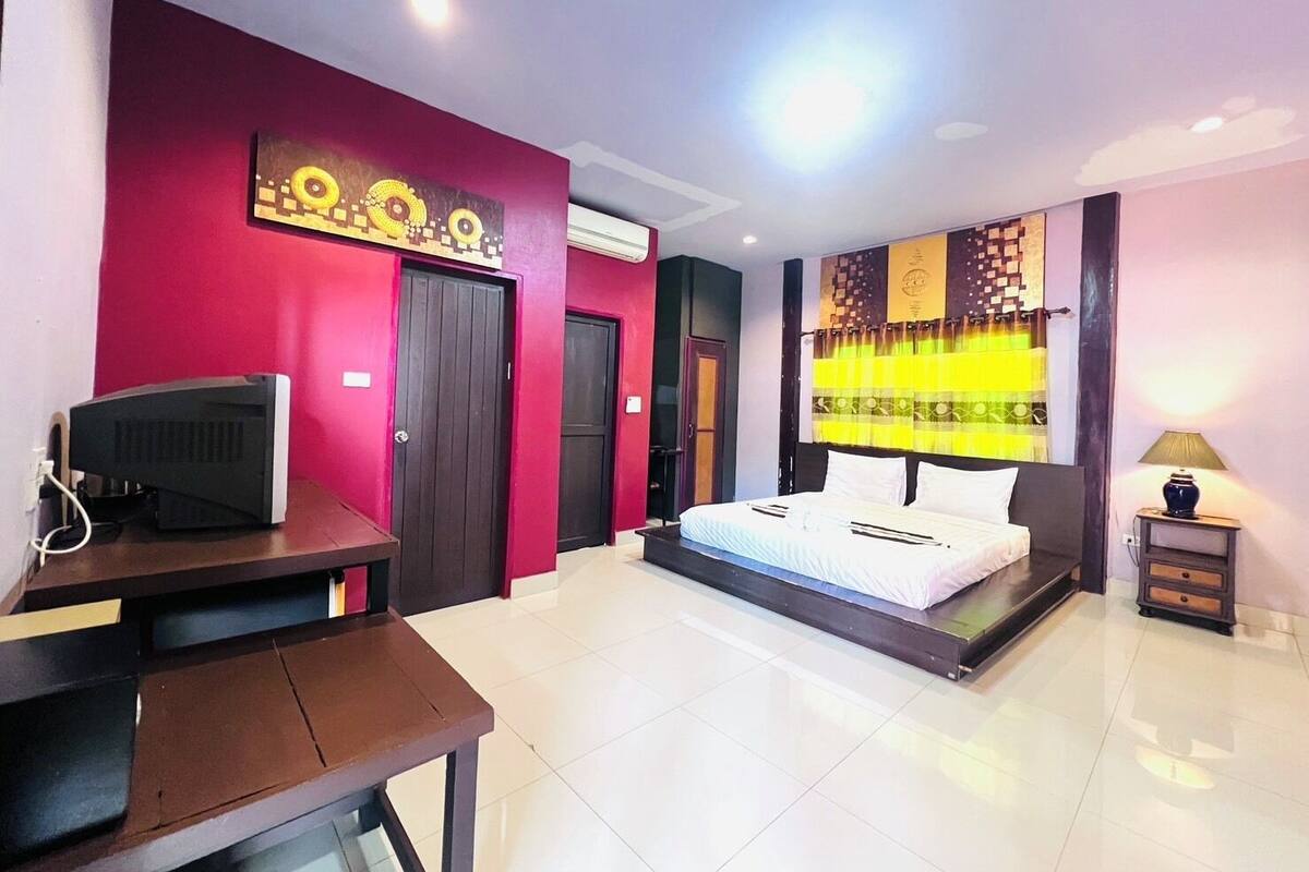 A hotel room with a bed, a desk, a television, and a wall with a decorative pattern.