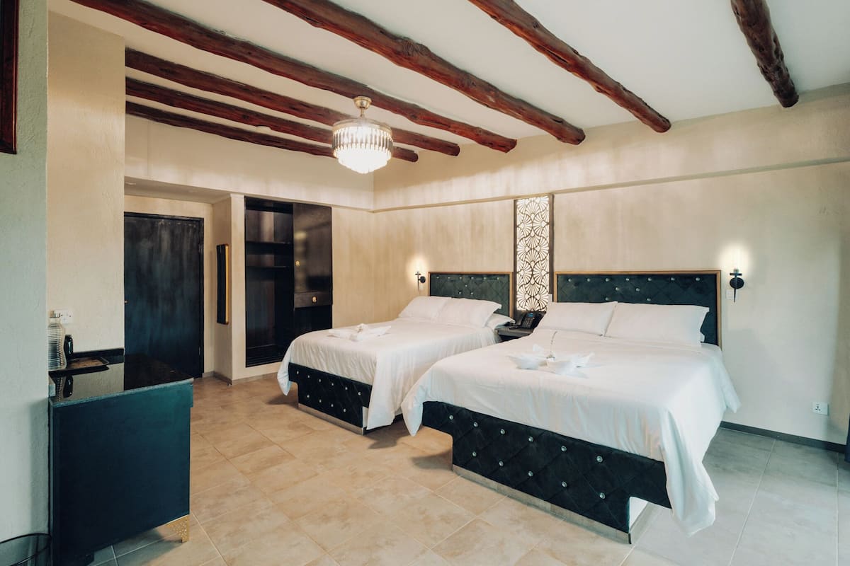 Une chambre avec deux lits, un lustre et un panneau décoratif au mur.