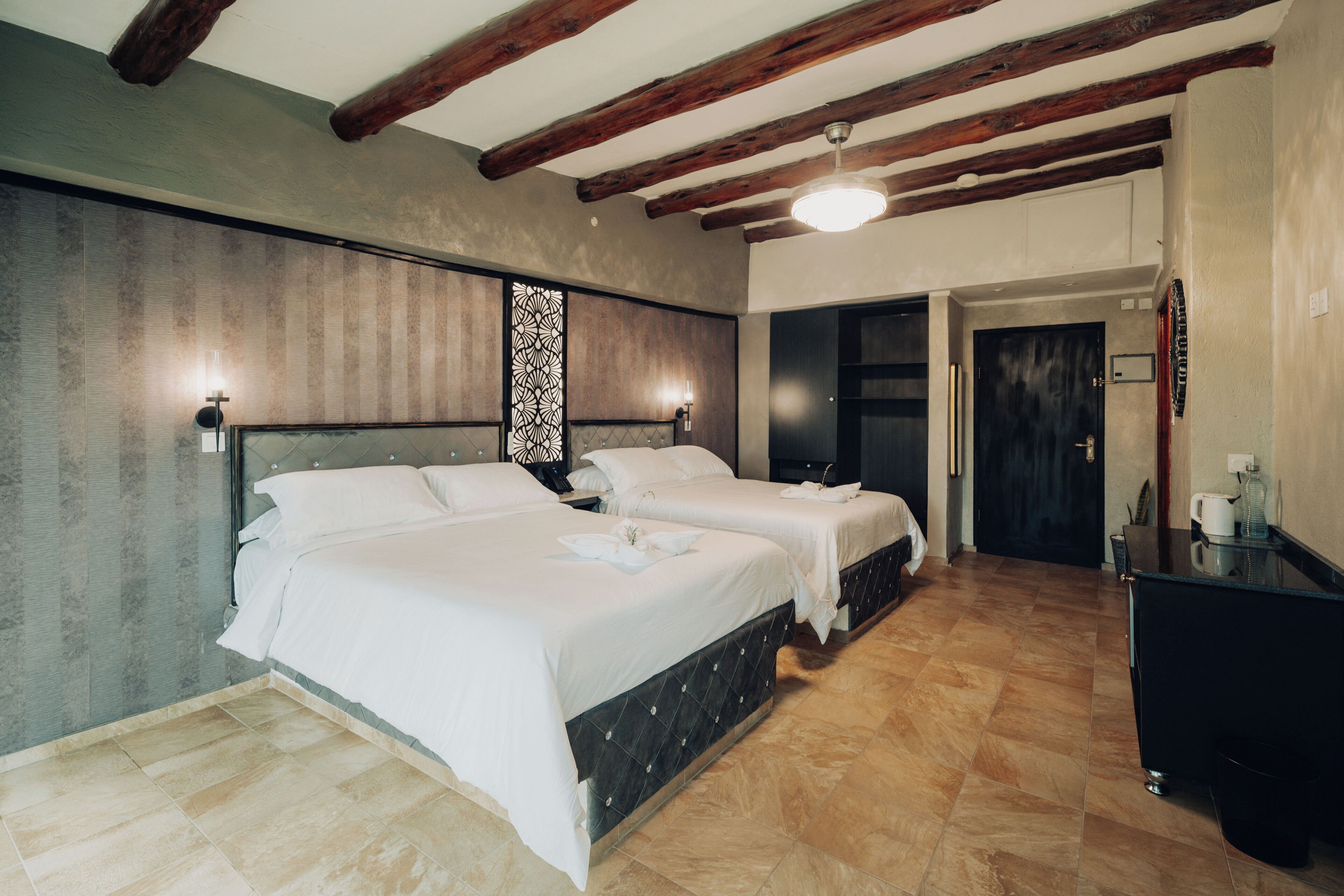 A hotel room with two beds, a desk, and a wardrobe.