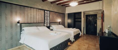 A hotel room with two beds, a desk, and a wardrobe.