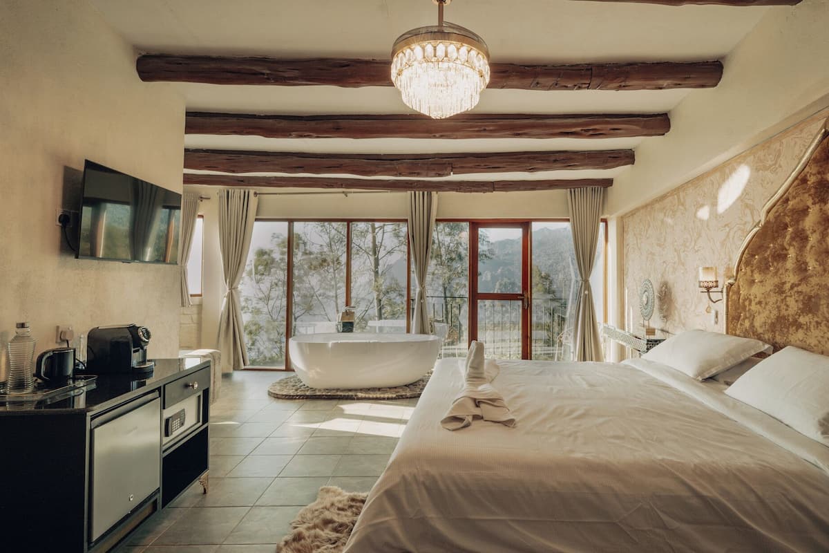 Une chambre avec un grand lit, une baignoire et un téléviseur fixé au mur.