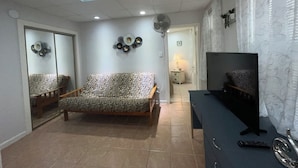 Una sala de estar con un sofá, un televisor, un ventilador y un espejo.