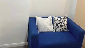 A blue sofa with two pillows, a white wall, and three abstract paintings. - 5 Bedroom Cosy Bloxwich Stay - Wifi & Free Parking (Walsall)