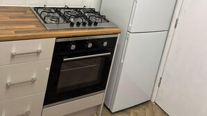 A compact kitchen with a gas stove, oven, and a white refrigerator. - 5 Bedroom Cosy Bloxwich Stay - Wifi & Free Parking (Walsall)