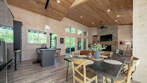 Une cuisine spacieuse avec un plancher en bois, un coin repas doté d’une grande table et de chaises, et une cheminée en pierre.