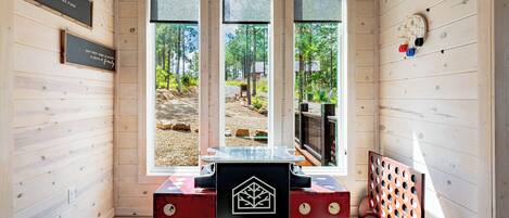 Interior de una cabaña de madera con una recepción identificada como 'BRICKYARD BRANCH', ventanas amplias y vistas a un área boscosa.