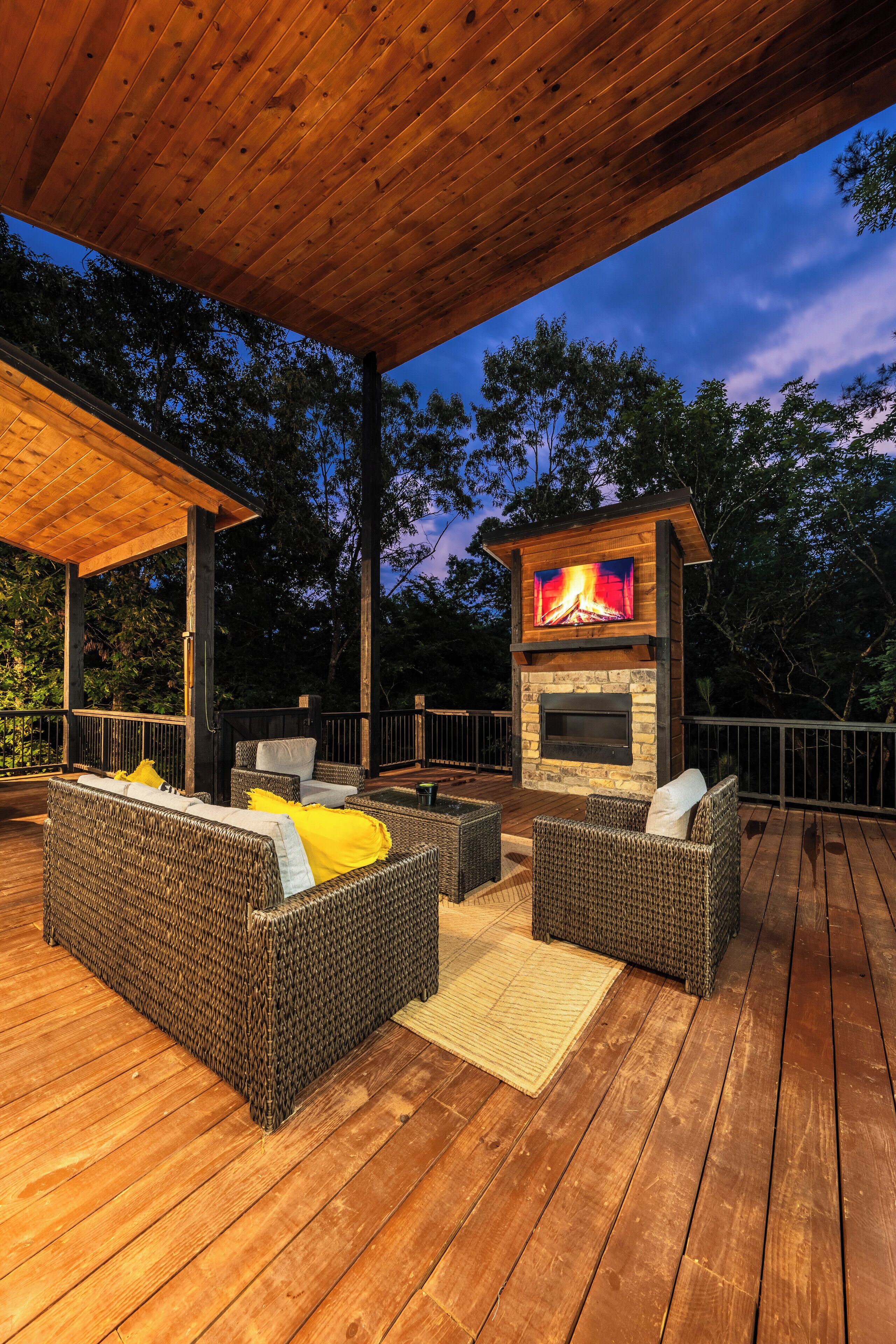 Une terrasse extérieure avec des meubles en osier et une cheminée en pierre.