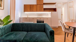 Eine moderne Küche mit Holzausstattung, einem eingebauten Ofen und einem Essbereich mit einem grünen Sofa und einem Tisch.