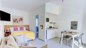 A modern hotel room with a bed, a sofa, a dining table with chairs, a kitchen area, and a TV mounted on the wall. - Vatican Loft with Balcony -Home and More (Rome)