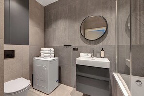 Un baño moderno con lavadora, lavamanos y retrete.