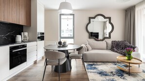 A modern kitchen with a dining area, a sofa, and a coffee table with books. - Lion Apartments - City Center (Gdansk)