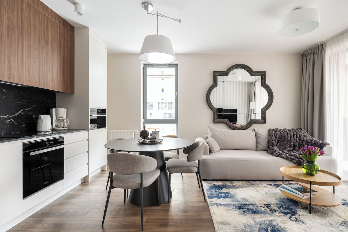 A modern kitchen with a dining area, a sofa, and a coffee table with books.