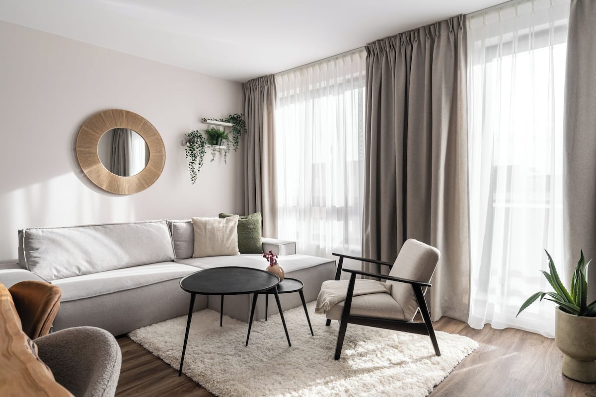 A modern living room with a sofa, a round mirror, a coffee table, and a chair.