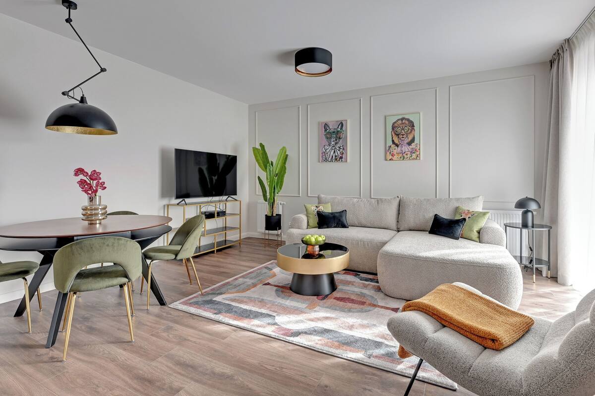 A modern living room with a round coffee table, a sofa, and a dining area with chairs and a TV.