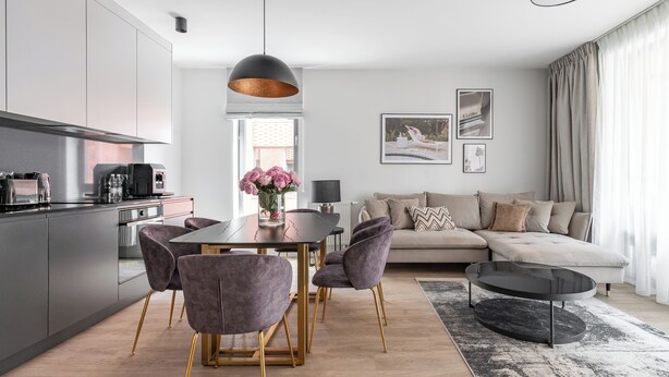 A modern living room with a sofa, a dining table with chairs, and a kitchen area with cabinets and appliances. - Lion Apartments - City Center (Gdansk)