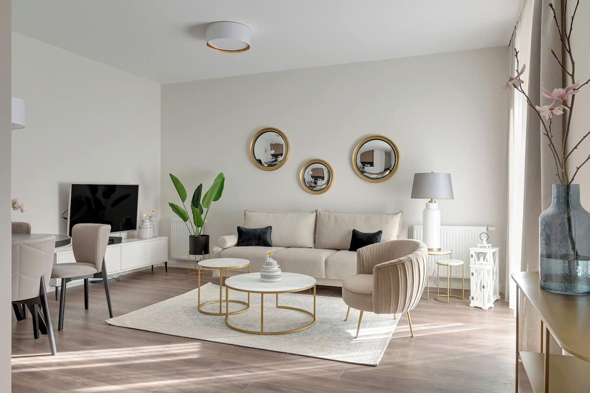 A modern living room with a sofa, two coffee tables, a TV, and decorative mirrors.