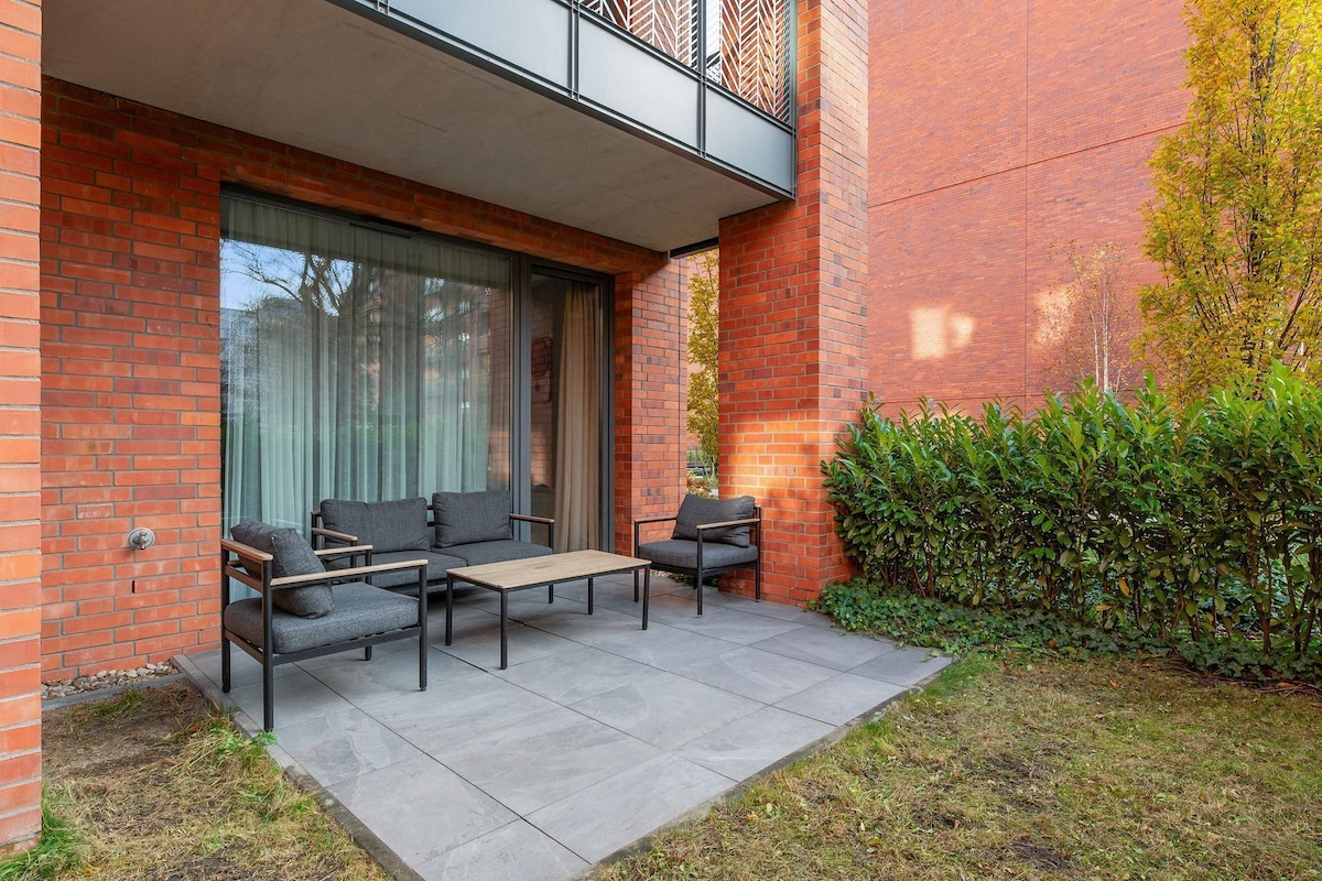 A modern outdoor seating area with a brick wall, a glass door, and a metal railing.