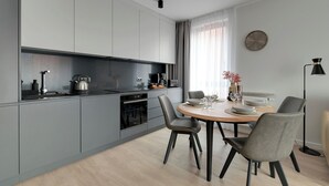 A modern kitchen with grey cabinets, a wooden dining table, and two chairs. - Lion Apartments - City Center (Gdansk)