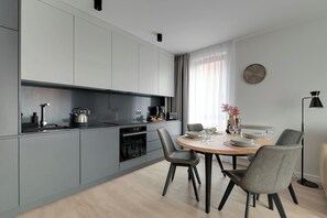 A modern kitchen with grey cabinets, a wooden dining table, and two chairs. - Lion Apartments - City Center (Gdansk)
