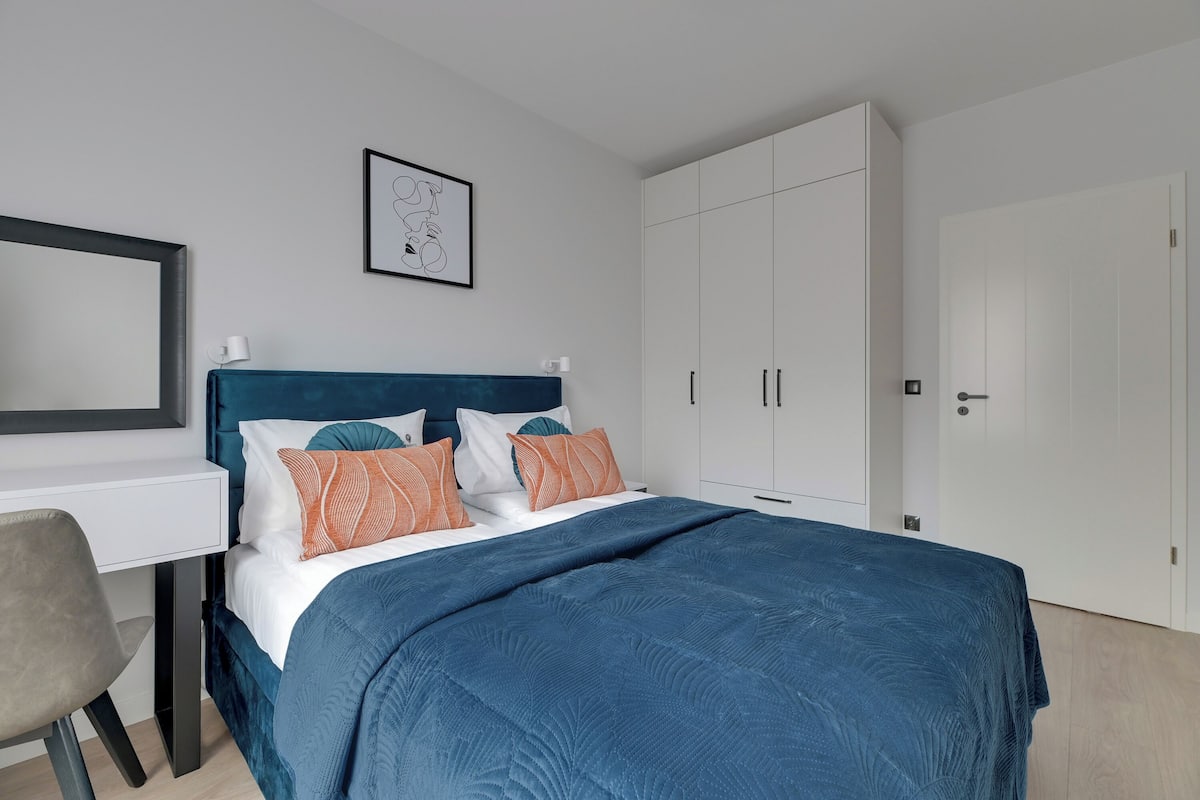 A modern bedroom with a bed, a desk, and a wardrobe.