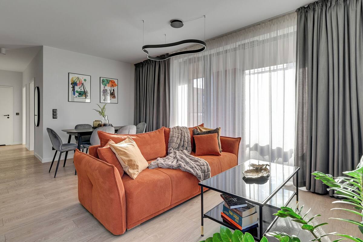 A modern living room with a sofa, coffee table, and dining area.