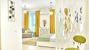 Un dormitorio moderno con cama, mesita de noche, sofá y un elemento decorativo en la pared.