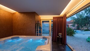 Ein Whirlpool mit Blick auf einen Garten und ein Gebäude im Hintergrund.