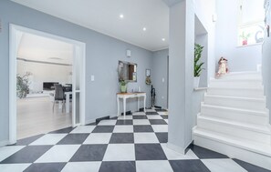 Stylish living space with a checkered floor, white staircase, and a flat-screen TV.