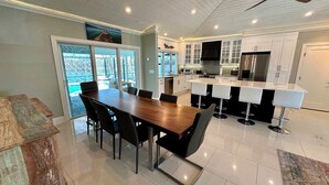 A modern kitchen with a large island, white cabinets, and a dining area with a wooden table and chairs. - Lagoon Getaway - Watch Dolphins Play (Fort Myers Beach)