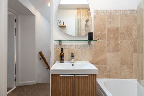 Ein modernes Badezimmer mit Waschbecken, Holz-Badmöbel, einer Glasablage und einer Duschkabine.