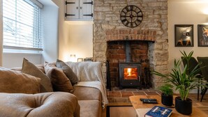 Ein gemütliches Wohnzimmer mit Kamin, Sofa, Couchtisch und Bücherregal.