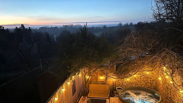 Eine Dachterrasse mit Whirlpool, Sitzgelegenheiten im Freien und Lichterketten.