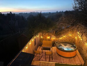 Eine Dachterrasse mit Whirlpool, Sitzgelegenheiten im Freien und Lichterketten.