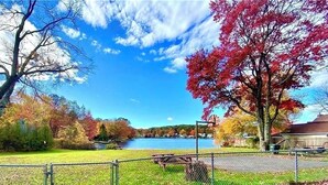 Un parque junto al lago con una mesa de picnic y un área cercada.