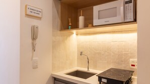 Une cuisine compacte équipée d’un four à micro-ondes, d’une plaque de cuisson intégrée, d’un évier et d’un téléphone.
